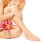 Female legs with pink lily isolated on white background